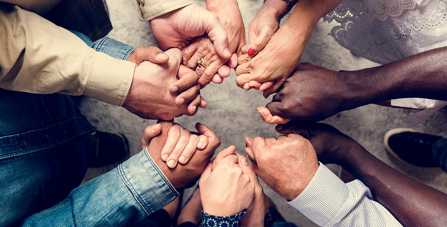 View from above of many team members holding hands (focused only on the hands)
